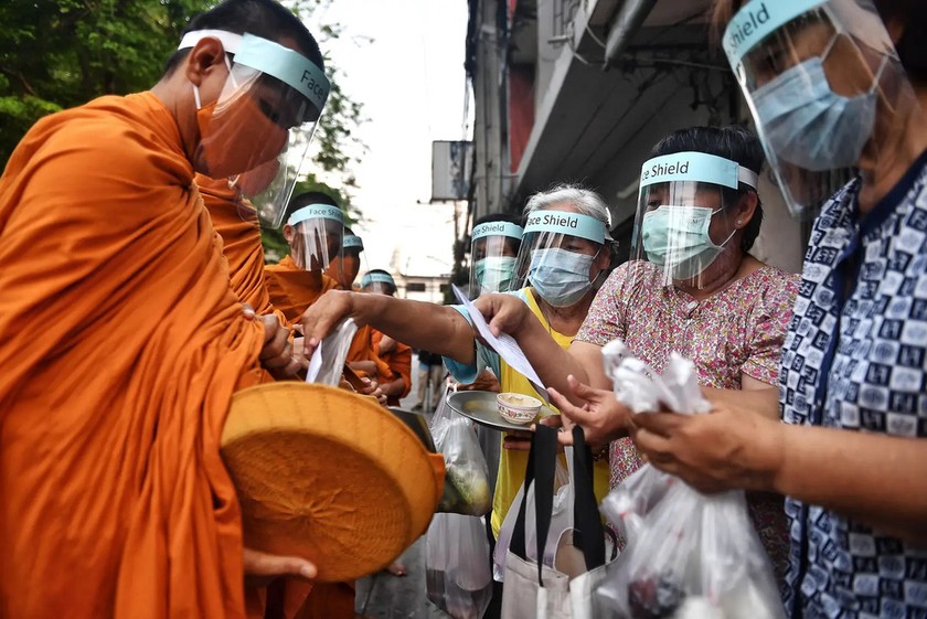Các nhà sư của chùa Wat Matchantikaram đeo mặt nạ che mặt khi đi cầu thực trên đường phố Bangkok, Thái Lan ngày 31-3-2020 - Ảnh GETTY IMAGES.