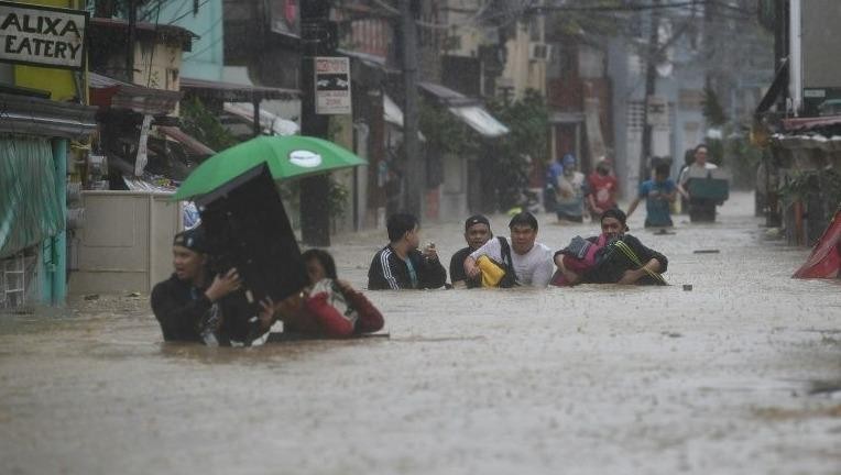 Người dân di chuyển trong nước lụt tại Manila.