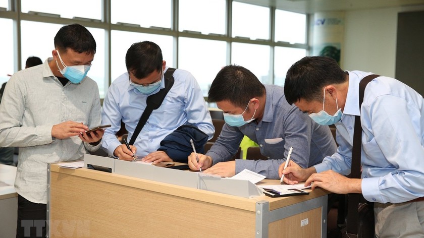 Nhân viên y tế kiểm tra phiếu khai báo y tế của hành khách trước khi làm thủ tục nhập cảnh tại cửa khẩu Nội Bài chiều 7/3.  (Hình: Dương Giang/TTXVN)