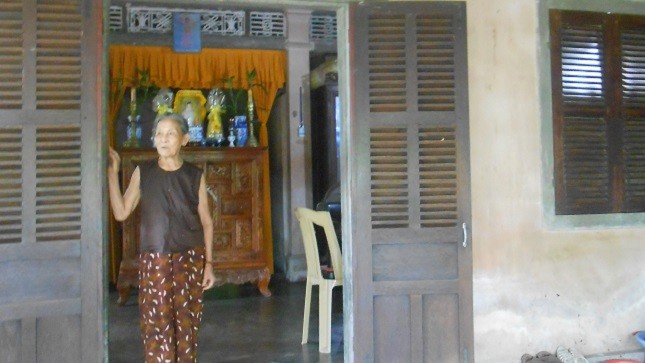 Người đàn bà 81 tuổi đứng trước ngôi nhà nhỏ của mình lòng đầy những nỗi niềm lo âu.