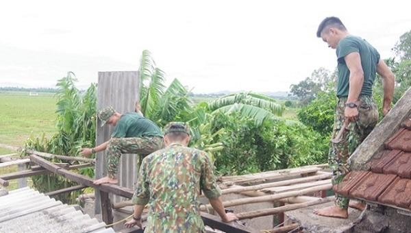 Các cán bộ chiến sĩ giúp người dân sửa lại mái nhà do ảnh hưởng của cơn bão số 5.