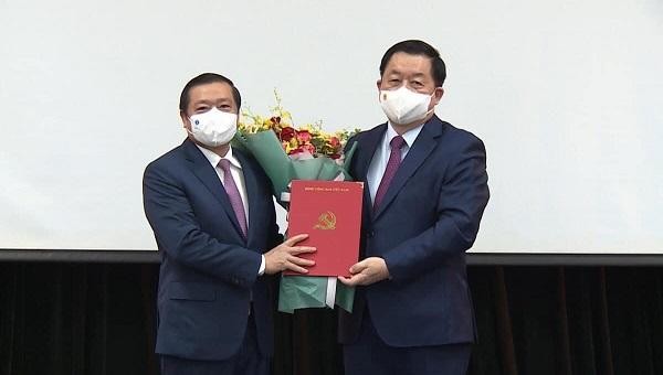 Trưởng Ban Tuyên giáo Trung ương Nguyễn Trọng Nghĩa trao quyết định và tặng hoa chúc mừng ông Lại Xuân Môn.