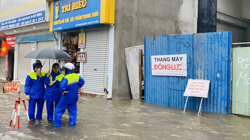 Nhân viên Công ty TNHH MTV Thoát nước Hải Phòng cảnh báo người đi đường tại các điểm ngập nguy hiểm.