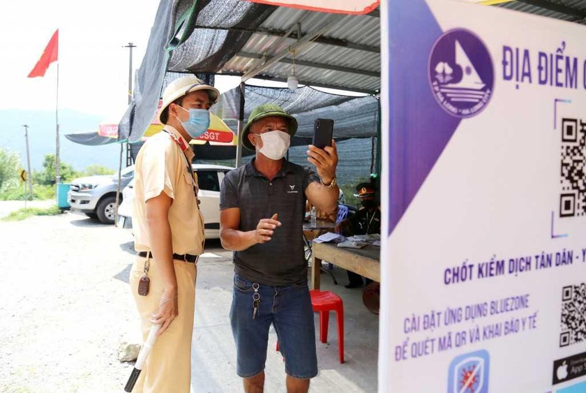 Cán bộ công an tỉnh Quảng Ninh hướng dẫn người dân quét mã QR qua chốt kiểm soát dịch COVID-19 trên Quốc lộ 279. Ảnh: Cổng TTĐT Quảng Ninh