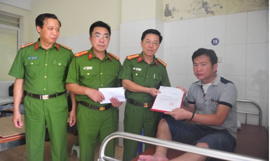 Đại tá Vũ Văn Đông, Phó Cục trưởng Cục Chính trị Cảnh sát trao quyết định khen thưởng của Tổng cục Cảnh sát cho đồng chí Lường Quang Học tại bệnh viện 198, Bộ Công an  