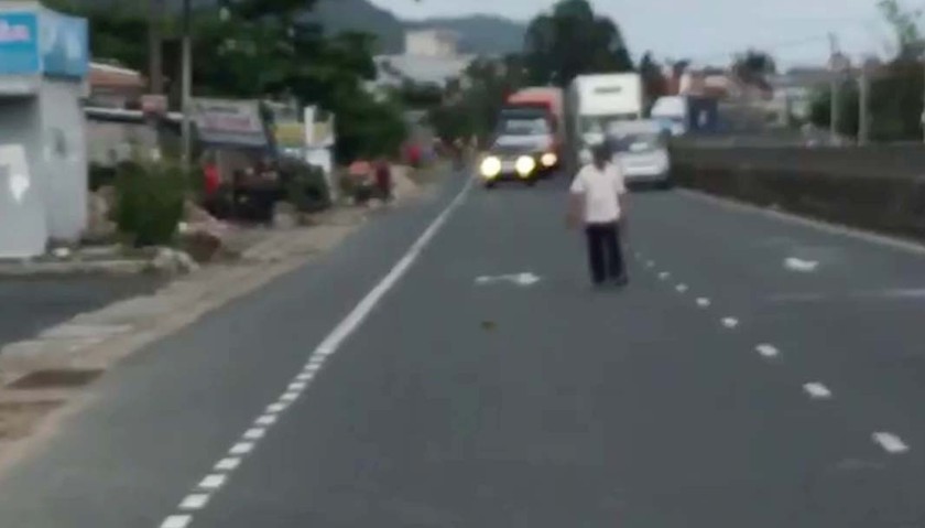 Người đàn ông cầm mã tấu, gạch đá chặn xe ô tô trên đường ( Ảnh cắt từ clip).