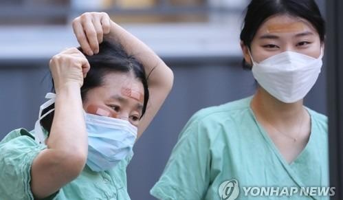 Nhân viên y tế Hàn Quốc sử dụng băng hỗ trợ để che vết thương trên mặt do đeo kính bảo hộ trong nhiều giờ trong khi điều trị bệnh nhân coronavirus .