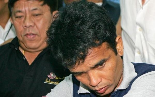 Somkid Pumpuang (Đang cúi mặt) bị cảnh sát bắt giữ