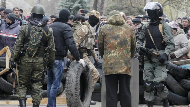 Những tay súng ủng hộ Nga chiếm tòa nhà cảnh sát ở Slovyansk và dựng rào chắn trong khi người dân đứng nhìn.  Ảnh: AP