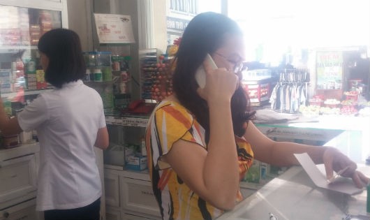 Người người phụ nữ  tự xưng là chủ nhà thuốc Thảo Trinh, đang gọi điện thoại lòng vòng cho ai đó và từ chối cung cấp thông tin cho phóng viên. Ảnh: Kim Oanh