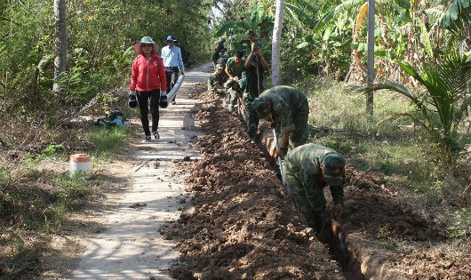 Cán bộ, đoàn viên thanh niên nhà trường giúp dân đào đường ống dẫn nước ở ấp Nam Chánh