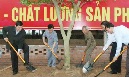 Cựu chiến binh Trần Thanh Hải (áo xám) cùng nguyên Chủ tịch nước Trương Tấn Sang, trồng cây lưu niệm tại Nhà máy gạch Nam Sơn. Ảnh: Hùng Minh