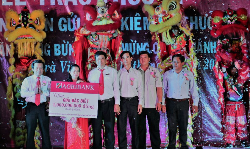 Ông Trần Ngọc Tồn, trưởng văn phòng đại diện Agribank khu vực Tây Nam Bộ (bìa trái) trao giải thưởng đặc biệt 01 tỷ đồng cho bà Bùi Thị Ửng