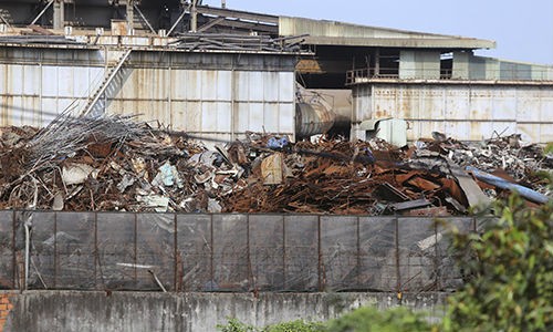 Nhiều tấn phế liệu được đổ sát tường rào của nhà máy thép giáp với khu dân cư ở Hòa Liên. Ảnh: Nguyễn Đông/VnE