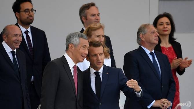 Tổng thống Pháp Emmanuel Macron (ở giữa) nói chuyện với Thủ tướng Singapore Lý Hiển Long trong cuộc diễu hành truyền thống kỷ niệm Ngày Quốc khánh Pháp ngày 14/7. Ảnh: AFP