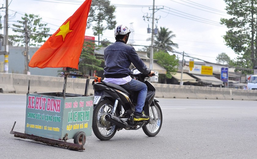 Một người tình nguyện kéo xe có gắn nam châm để dọn đinh trên quốc lộ nhằm chống nạn “đinh tặc”