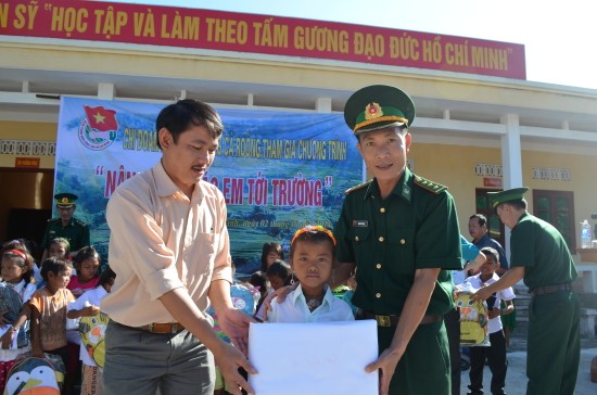 Đại úy Trịnh Tứ Thắng trao quà cho học sinh nghèo ở biên giới Quảng Bình. 
Ảnh: Viết Hà