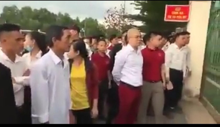 Ông Nguyễn Thái Luyện (áo trắng, quần đỏ) và nhóm người tụ tập đòi người trước trụ sở công an (ảnh cắt từ clip)