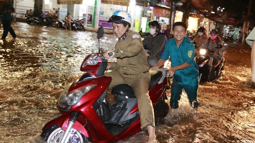 Dân quân tự vệ đẩy xe hỗ trợ người dân vượt đoạn ngập nước