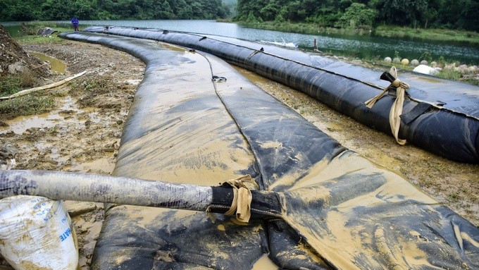 Hút bùn nhiễm dầu thải trên kênh dẫn nước vào Nhà máy nước sông Đà.
 (Hình:vnexpress.net)
