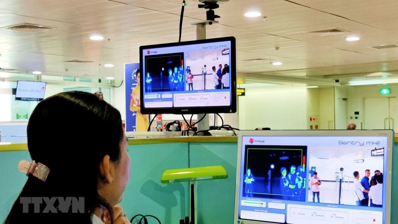 Nhân viên sân bay Tân Sơn Nhất theo dõi trên màn hình hiển thị máy quét thân nhiệt đối với hành khách quốc tế đến Việt Nam. (Ảnh: Đinh Hằng/TTXVN)