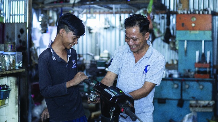 Thay vì việc phải bán dạo trên đường, Thanh đang được học nghề cơ khí tại một tiệm sửa xe máy tại địa phương