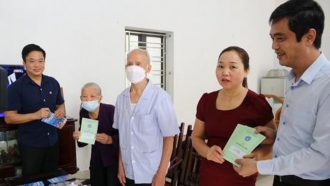 Bà Phạm Thị Loan và người thân nhận sổ BHXH tự nguyện.