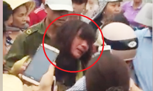 Hàng chục người vây một phụ nữ bị còng tay.