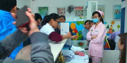 Phụ huynh nộp danh sách đăng ký tiêm vắc xin 5in1 cho nhân viên y tế tại điểm tiêm chủng Vĩnh Hưng.
