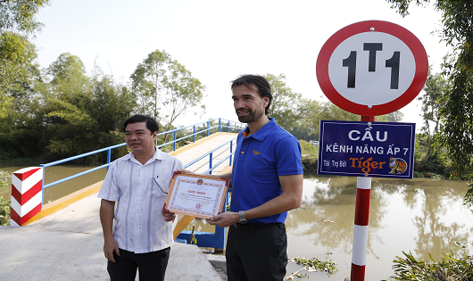 Đại diện HEINEKEN Việt Nam và ông Nguyễn Thanh Hải - Phó Trưởng đoàn Đại biểu Quốc hội tỉnh Tiền Giang bên cây cầu được tái chế từ nắp chai bia Tiger