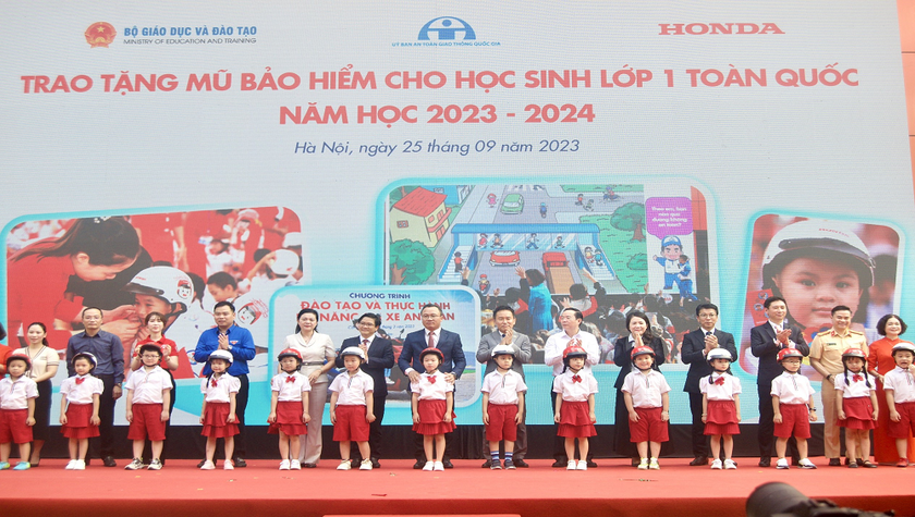 Các đại biểu trao tặng mũ bảo hiểm cho các em học sinh lớp Một trường Tiểu học Phú Đô