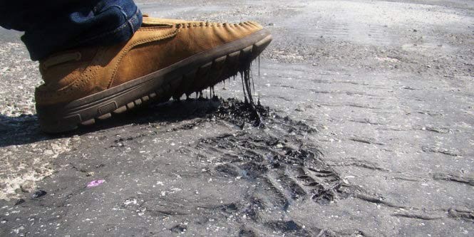 Nhựa đường chảy vì nắng nóng dính chặt vào giày người đi đường - Ảnh: Văn Định