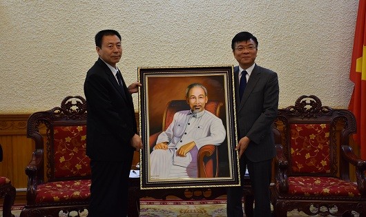 Chủ nhiệm Chính trị Bộ Tư pháp Trung Quốc Lô Ơn Quang (bên trái) nhận quà lưu niệm là bức tranh vẽ Chủ tịch Hồ Chí Minh từ Bộ trưởng Bộ Tư pháp Việt Nam Lê Thành Long.