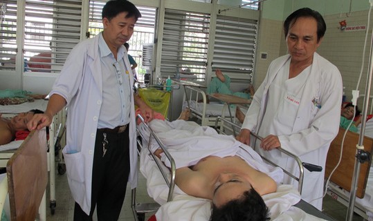 Bác sĩ Vũ (phải) và bác sĩ Trí thăm hỏi bệnh nhân sau ca phẫu thuật.