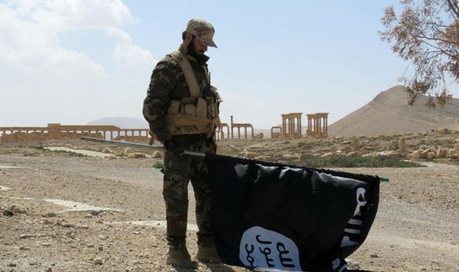 Một binh sĩ Syria hạ lá cờ IS tại thành phố cổ Palmyra (Nguồn: Independent)