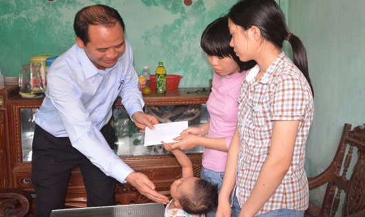 Ông Nguyễn Văn Hồi, Cục trưởng Cục Bảo trợ xã hội thuộc Bộ LĐ-TB&XH, thăm hỏi, trao quà của Thủ tướng Chính phủ cho ba chị em Sáng. Ảnh Tuổi trẻ