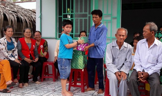 Bé Nhật Huy, thành viên “nhí” của CLB trao quà cho các hộ nghèo