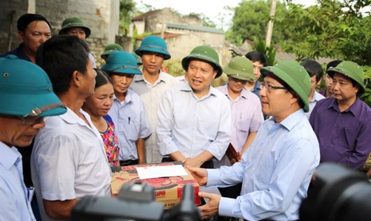 Phó Thủ tướng Phạm Bình Minh động viên, tặng quà các gia đình có hoàn cảnh khó khăn bị thiệt hại do mưa lũ. Ảnh: VGP