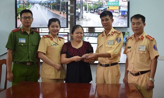 Các chiến sĩ Cảnh sát giao thông giao trả tiền cho bà Hoàng Thị Bích Thủy. Ảnh: Cổng thông tin Bộ Công an