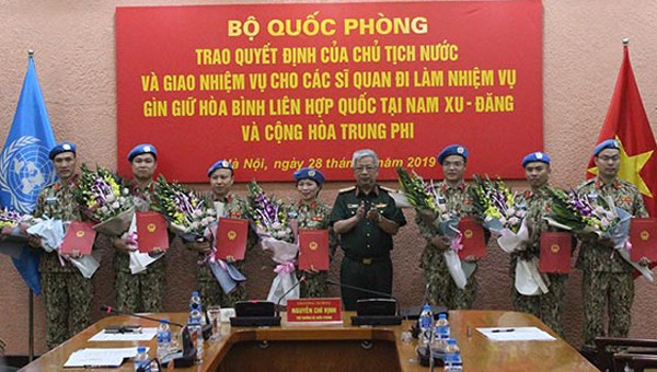 Thượng tướng Nguyễn Chí Vịnh trao Quyết định của Chủ tịch nước và tặng hoa 7 sĩ quan đi làm nhiệm vụ gìn giữ hòa bình Liên hợp quốc tại Nam Xu-đăng và Cộng hòa Trung Phi. Ảnh: Cổng thông tin Bộ Quốc phòng.