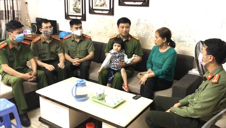 Trung tá Trương Thụy Hải (bế cháu bé) cùng cán bộ chiến sỹ Công an huyện Văn Bàn đến thăm cháu bé sau 2 ngày ra viện. Ảnh: Công an tỉnh Lào Cai.