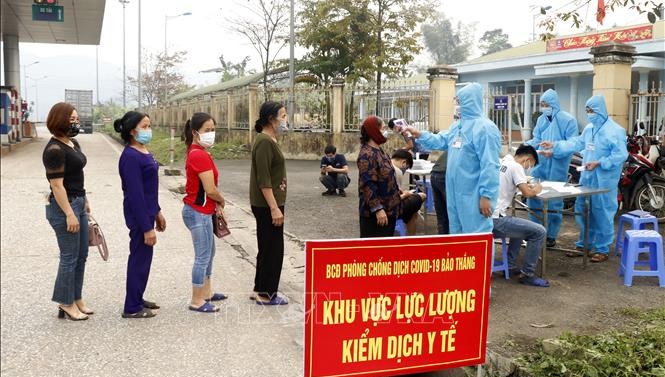 Người dân và hành khách được kiểm tra thân nhiệt tại chốt nút giao đường cao tốc Nội Bài - Lào Cai thuộc địa phận xã Xuân Giao, huyện Bảo Thắng (Km234). Ảnh: Quốc Khánh/TTXVN.