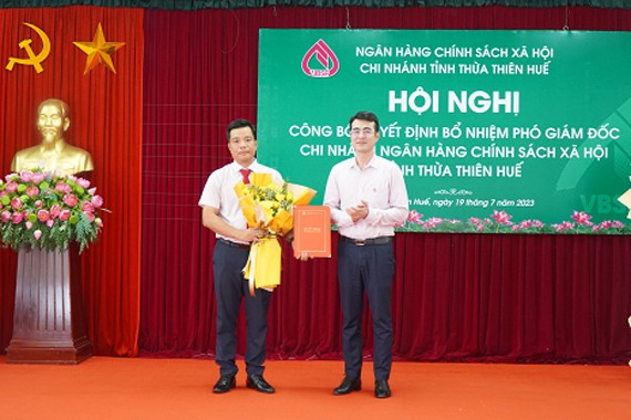 Phó Tổng Giám đốc Ngân hàng Chính sách Xã hội Việt Nam Nguyễn Đức Hải trao quyết định và tặng hoa chúc mừng ông Đào Bá Thuận.