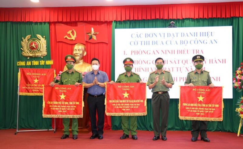 Chủ tịch UBND tỉnh Nguyễn Thanh Ngọc và Đại tá Nguyễn Văn Trãi trao cờ thi đua xuất sắc của Bộ Công an cho các tập thể. Ảnh: CAND