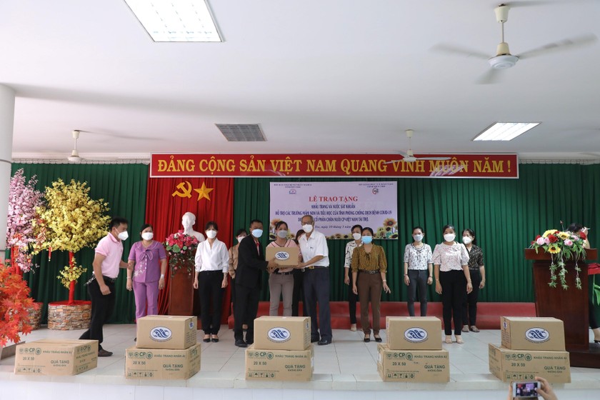 Ông Witthawat Satthatham (vest đen), đại diện C.P. Việt Nam trao tặng tượng trưng khẩu trang, nước sát khuẩn cho các trường