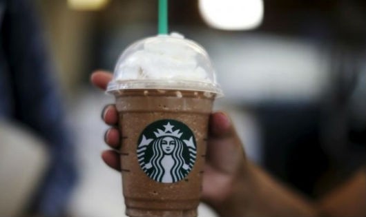 Một phụ nữ cầm trên tay cốc Frappuccino tại một cửa hàng Starbucks ngày 27/10/2015. (Reuters / Lucy Nicholson)