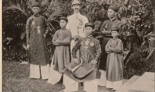 Vua Thành Thái (ngồi) và ba người em trai (từ trái qua): Bửu Trang, Bửu Liêm, và Bửu Lũy. Đứng phía sau là sĩ quan bảo vệ và người phiên dịch.