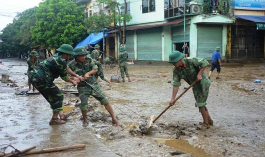 Cán bộ, chiến sĩ Trung đoàn 174 giúp nhân dân nạo vét bùn đất sau mưa lũ.