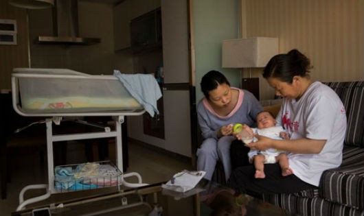 Bảo mẫu (phải) hướng dẫn bà mẹ trẻ cách chăm sóc trẻ sơ sinh ở Bắc Kinh