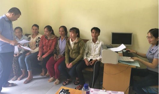 Cán bộ BHXH huyện Con Cuông in và cấp lại thẻ BHYT cho bà con xã Cam Lâm.